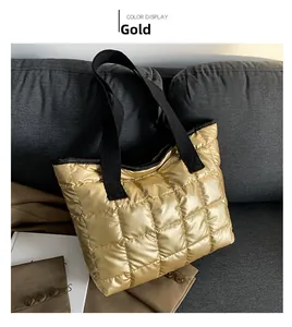Detail of gold quilted tote bag with metallic finish and black wide fabric handles