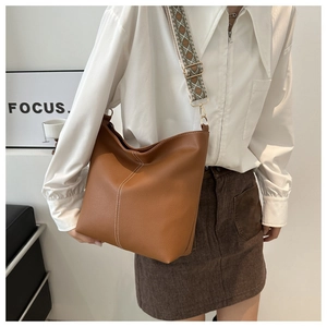 Detail of brown leather bucket bag with white V-stitching and geometric jacquard strap