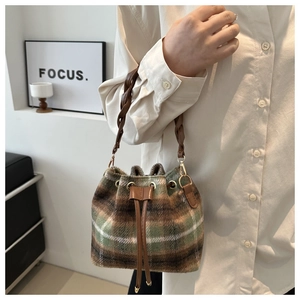 Détail du sac seau à carreaux en laine avec anse tressée en cuir marron et cordon
