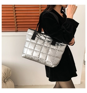 Detail der silbernen gesteppten Tragetasche mit Metallic-Finish und schwarzem Webgriff