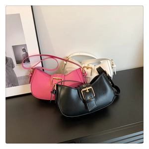 Close-up of three half-moon shoulder bags in black, pink, and white with large gold buckles