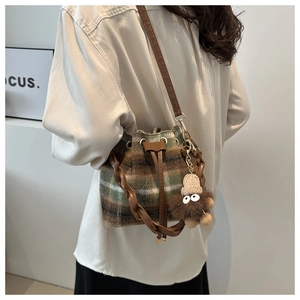 Détail d'un sac seau à carreaux avec fermeture à cordon et breloque petit monstre