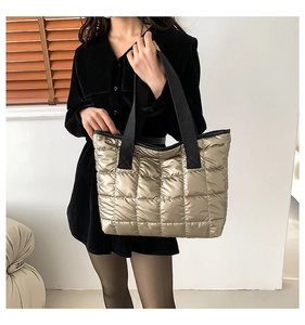 Detailaufnahme der champagnergoldenen Stepp-Tote-Bag mit einem breiten schwarzen Schultergurt