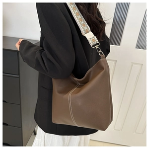 Detail of coffee bucket bag with white contrast stitching and ethnic pattern wide strap