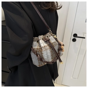 Détail d'un sac seau vintage à carreaux en peluche avec anse en cuir tressé