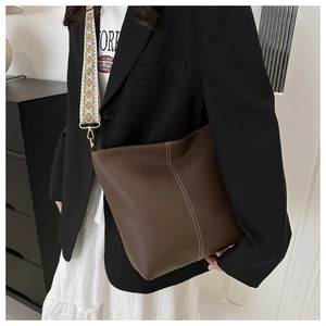 Brown leather bucket bag with white contrast stitching and ethnic embroidery strap