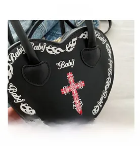 Detail of black heart bag with cross print, baby lettering and flame pattern texture