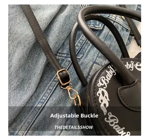 Close-up of golden metal buckle and adjustable leather strap on black Baby shoulder bag