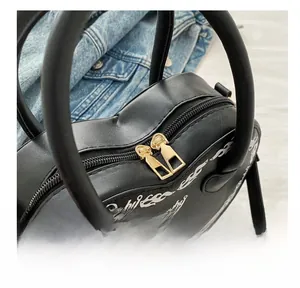 Close-up of the smooth golden double zippers and white flame print on heart handbag