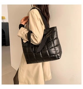 Gesteppte schwarze Puffer-Tasche aus glänzendem Nylon, von einem Model getragen