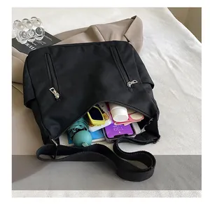 Vue détaillée montrant la grande capacité du sac à bandoulière en nylon noir avec poches