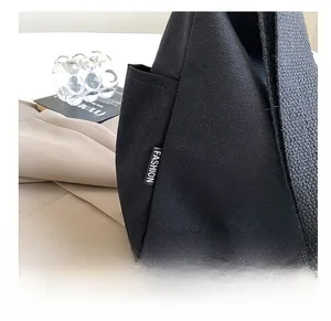 Détail de la texture en toile et de l'étiquette tissée sur le sac à bandoulière noir