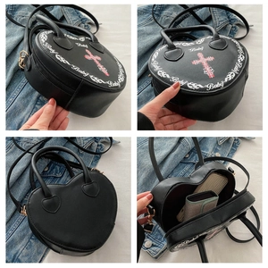 Detail view of black heart-shaped handbag featuring cross print and internal storage space