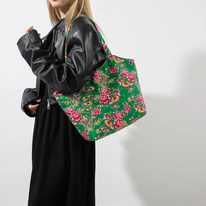 Grüne Tragetasche im Ethno-Stil mit Blumenmuster getragen von Model im schwarzen Outfit