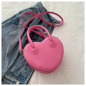 Detailed close-up of pink heart-shaped bag with gold hardware on white fabric