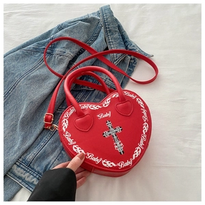 Close-up of red heart-shaped handbag featuring cross print and Baby lettering detail