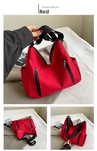 Détail du sac cabas en toile rouge avec larges anses noires et poches zippées décoratives