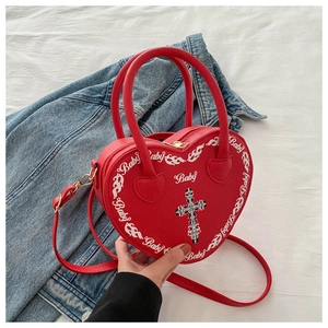 Detailed close-up of heart-shaped red bag with gothic cross and gold metal zipper hardware