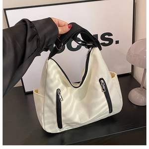 Détail du sac hobo en toile blanc cassé avec bandoulière noire et fermetures éclair argent