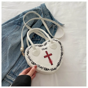 Detail of heart-shaped handbag with red gothic cross and baby print on white faux leather