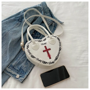 Detail of white heart-shaped bag with Y2K Baby print and cross on textured fabric
