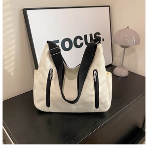 Détail du sac cabas en toile blanc cassé avec fermetures éclair noires et poches latérales
