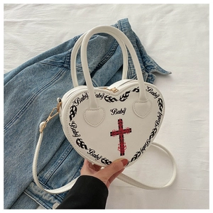 Close-up of heart-shaped bag featuring gothic cross print and Baby letter patterns