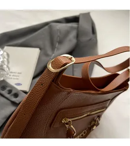 Detail of brown litchi pattern leather tote strap with golden oval buckle and chain