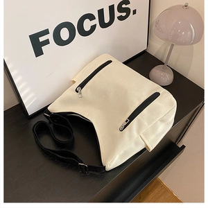 Gros plan du sac cabas en toile beige avec double poche zippée noire et sangle réglable