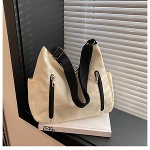 Gros plan détaillé du sac cabas en toile crème avec des accents de fermeture éclair noire