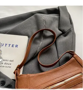 Detail view of brown lychee grain texture and gold zipper on commute shoulder bag