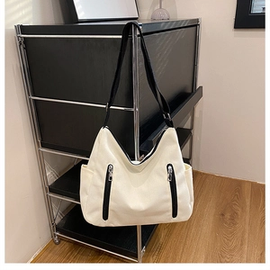 Vue détaillée du sac hobo crème avec bretelles en nylon noir et doubles zips frontaux