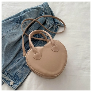 Detailed close-up of beige heart-shaped PU leather handbag with elegant top handles