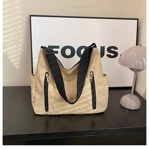 Détail d'un sac cabas en toile beige avec anses noires et poches zippées verticales