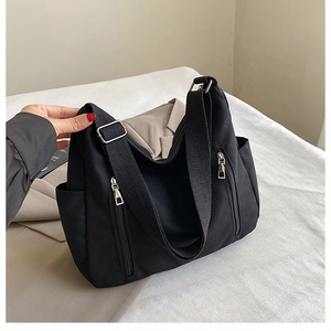 Détail du sac cabas en toile noire montrant les poches latérales et les boucles de réglage
