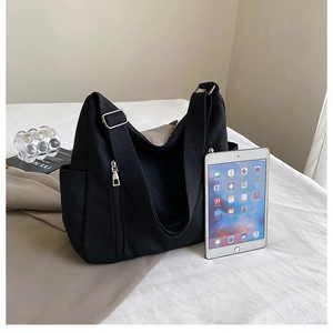 Détail du sac cabas en toile noire montrant la poche latérale et le zip frontal