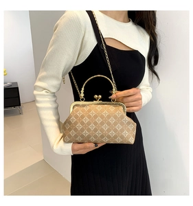 Dettaglio borsa vintage marrone con motivi a trifoglio e manico in metallo dorato