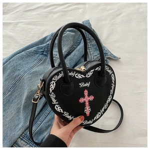 Close-up of heart-shaped handbag with cross print and baby lettering detail