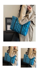 Detail of royal blue quilted tote bag with metallic finish and black shoulder straps