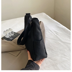 Détail d'un sac bandoulière en toile noire avec large sangle et poche latérale