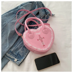 Detail view of heart-shaped pink purse with red cross print and Baby text on a flat lay
