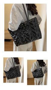 Detail of black quilted tote bag showing glossy nylon fabric and spacious design