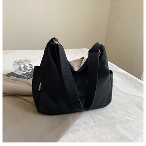 Vue détaillée du sac hobo en toile noire avec large bandoulière et étiquette FASHION chic
