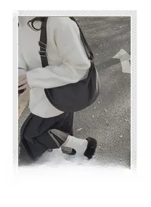 Street style view of a black crescent crossbody bag with adjustable wide shoulder strap