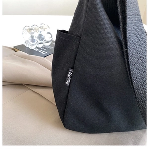 Détail du sac cabas en toile noire avec étiquette mode et poche latérale pratique