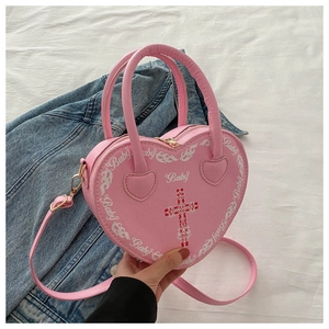 Detail of pink heart-shaped bag with red cross pattern and top handle design