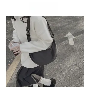 Minimalist black crescent crossbody bag with adjustable wide fabric strap on a model