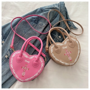 Detail view of heart-shaped crossbody bags in pink and beige with Baby print and cross