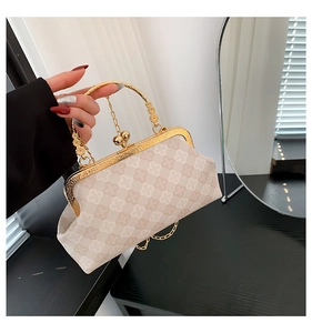 Dettaglio borsa beige con motivo a quadrifoglio sbalzato, telaio dorato e chiusura a sfera
