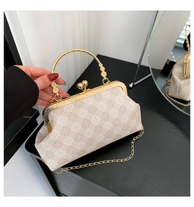 Dettaglio borsa beige con stampa trifoglio, manico floreale oro e catenina